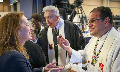 Bishop Héctor A. Burgos Núñez, who leads the Upper New York and Susquehanna conferences, distributes communion to participants during opening worship service on April 23, 2024, at General Conference in Charlotte, N.C. Next to him, also distributing communion, is Horizon Texas Conference Bishop Rubén Saenz Jr., who is now the Council of Bishops president. A United Methodist leadership body recommends that the U.S. have 34 bishops starting in 2028. File photo by Paul Jeffrey, UM News.