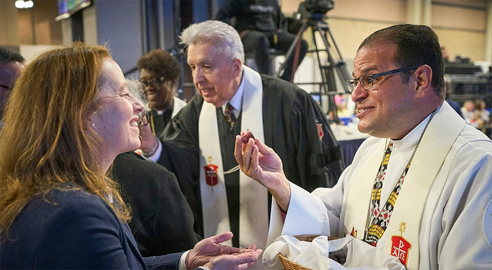 Bishop Héctor A. Burgos Núñez, who leads the Upper New York and Susquehanna conferences, distributes communion to participants during opening worship service on April 23, 2024, at General Conference in Charlotte, N.C. Next to him, also distributing communion, is Horizon Texas Conference Bishop Rubén Saenz Jr., who is now the Council of Bishops president. A United Methodist leadership body recommends that the U.S. have 34 bishops starting in 2028. File photo by Paul Jeffrey, UM News.